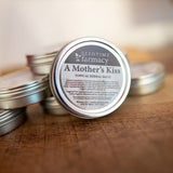 Herbal Salve on Wooden Table: A Mother's Kiss by Seedtime Farmacy - Topical Herbal Salve for Cuts, Rashes, Burns and Outerdermis Support. Formulated by Dori Marietta, herbalist in Winston, GA.